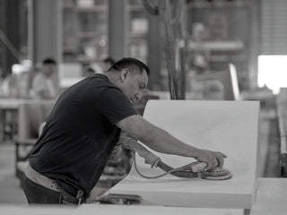 Person in the Trueform facility working on finishing a curved concrete piece.