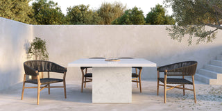 Sunken outdoor patio with square pedestal concrete table and rattan chairs.