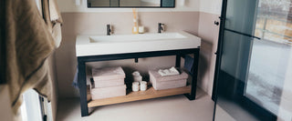 Double faucet rectangular concrete sink with black steel base and open wood shelf, styled in a warm modern bathroom—ideal for residential master baths, boutique hotels, and designer remodels