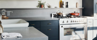 Modern kitchen featuring dark concrete countertops with matte finish, deep blue cabinetry, farmhouse sink, and stainless steel range—perfect for upscale residential projects and contemporary kitchen remodels.