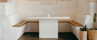 White concrete pedestal table in a Southwest-styled restaurant alcove with stucco walls, integrated wood bench seating, and warm ambient lighting—ideal for boutique hospitality, custom dining spaces, and modern desert-inspired interiors