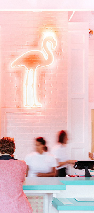 Restaurant bar with pink walls and aqua blue concrete countertops.